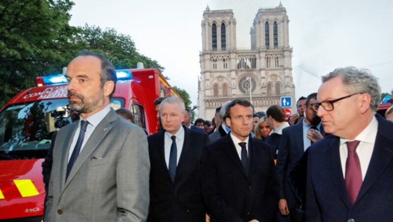 Der Schock steht ihm ins Gesicht geschrieben: Frankreichs Präsident Macron vor der brennenden Kathedrale von Notre Dame (Bild: PHILIPPE WOJAZER/POOL/AFP)