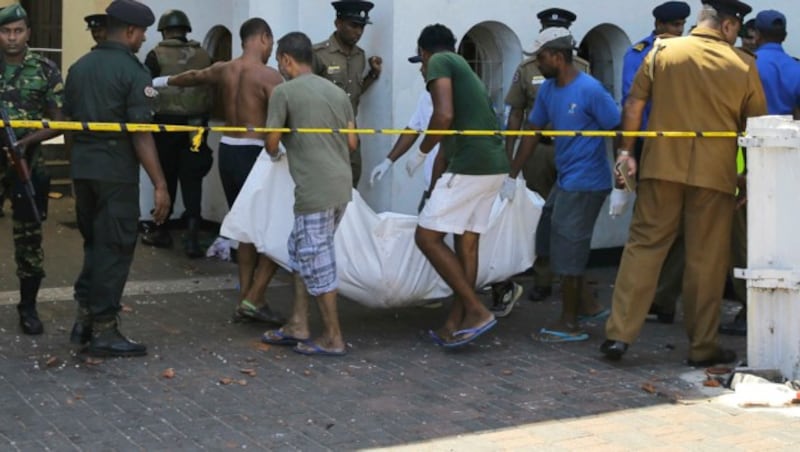 Helfer tragen ein Todesopfer aus der St. Anthony‘s Church. (Bild: AP)