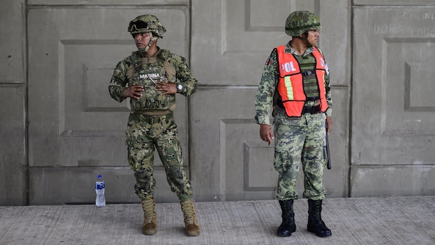 Ein Beamter der Marine und einer des Militärs halten an einem Checkpoint nach Reisenden ohne Dokumente Ausschau. (Bild: AFP )