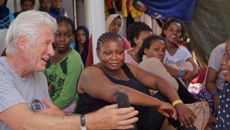 Richard Gere im Gespräch mit den geretteten Migranten auf der Open Arms (Bild: AP)