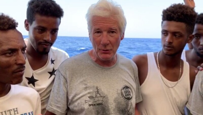 Richard Gere im Gespräch mit den geretteten Migranten auf der Open Arms (Bild: AFP)