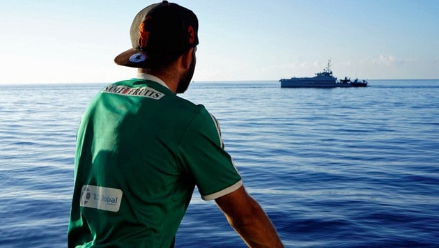 Ein Migrant beobachtet die italienische Küstenwache. (Bild: AP)