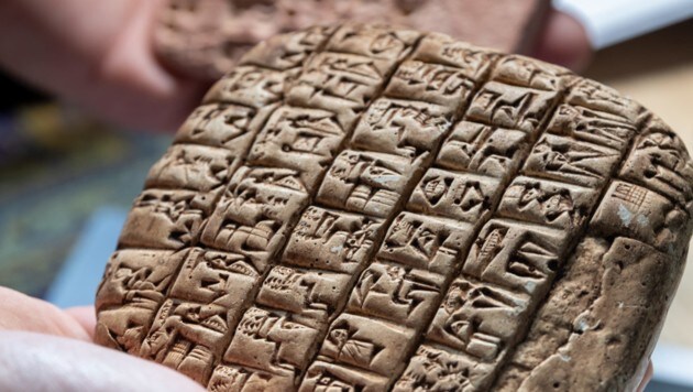 Enrique Jimenez hält zwei beschriebene Tontafel-Replikate aus Mesopotamien in der Hand, dessen Texte mit künstlicher Intelligenz wiederhergestellt werden sollen. (Bild: APA (dpa))