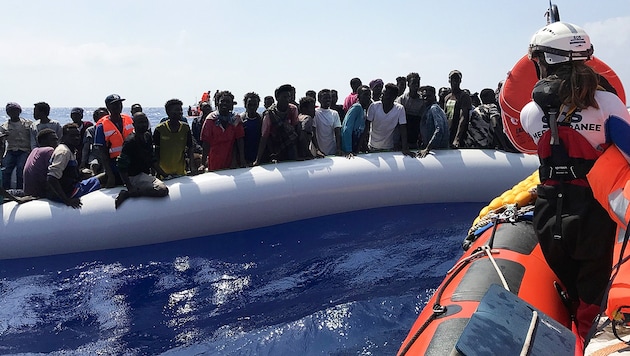 Ein Crewmitglied der Ocean Viking bei der Rettung von Migranten in einem Schlauchboot (Bild: AFP )