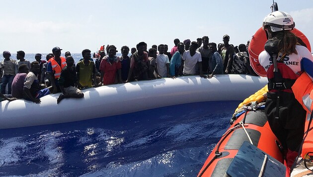 Ein Crewmitglied der Ocean Viking bei der Rettung von Migranten in einem Schlauchboot (Bild: AFP)