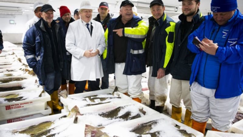 Boris Johnson mit weißem Mantel und Hut in der Halle des Peterhead Fish Market (Bild: AFP)