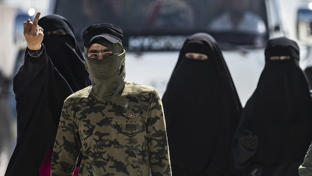 Women of IS fighters (in the background) guarded by a security guard in the al-Hol camp in Syria (Bild: AFP)