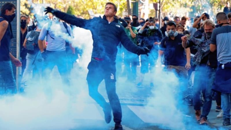 Dieser Demonstrant will seine Kameraden retten und wirft einen Tränengaskanister wieder in Richtung Polizei. (Bild: AFP)