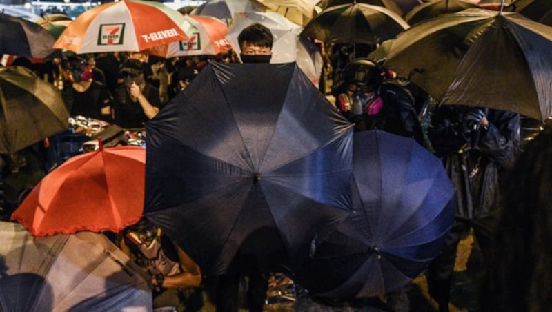 Die Demonstranten der „Regenschirmbewegung“ wehren mit ihren Schirmen Pfefferspray ab. (Bild: APA/AFP/Mohd RASFAN)