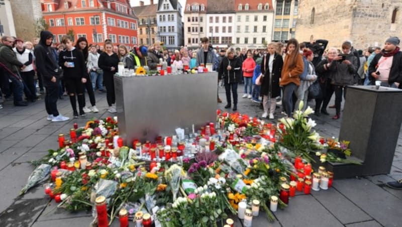 Menschen legen als Zeichen der Trauer Blumen am Marktplatz in Halle ab und entzünden Kerzen. (Bild: APA/dpa/Hendrik Schmidt)