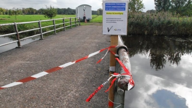 Ein Absperrband der Polizei sichert eine Brücke über einen kleinen Bach, die zu dem Anwesen in Ruinerwold führt. (Bild: Andreas Schiel)