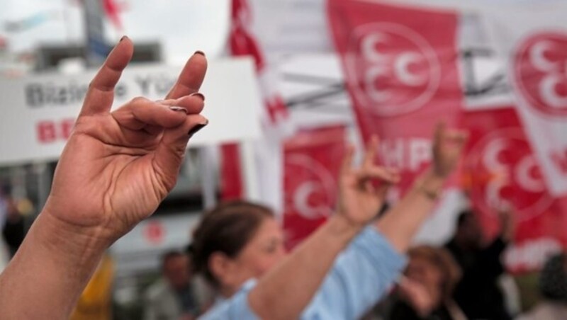 Der „Wolfsgruß“ ist das Merkmal und Erkennungszeichen der „Grauen Wölfe“. Er stellt einen Wolfskopf dar. Der Gründer der Bewegung, Alparslan Türkes, meinte dazu: „Der kleine Finger symbolisiert die Türken, der Zeigefinger den Islam, der Kreis die Welt. Der Punkt, an dem sich die drei Finger treffen, ist der Stempel, mit dem wir der Welt den türkischen Islam aufdrücken.“ (Bild: AP)