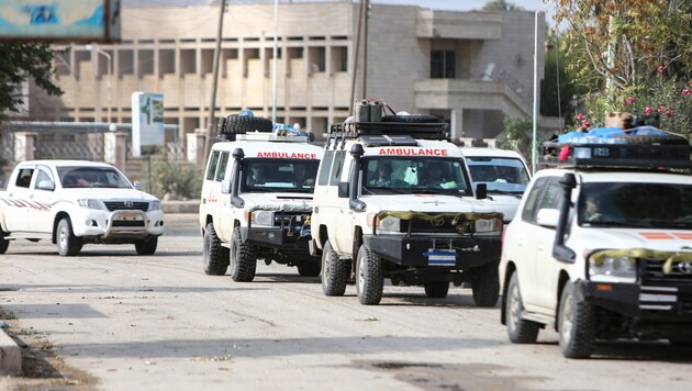 Die abziehenden Kämpfer werden von Rettungsfahrzeugen begleitet. (Bild: APA/AFP/Nazeer Al-khatib)