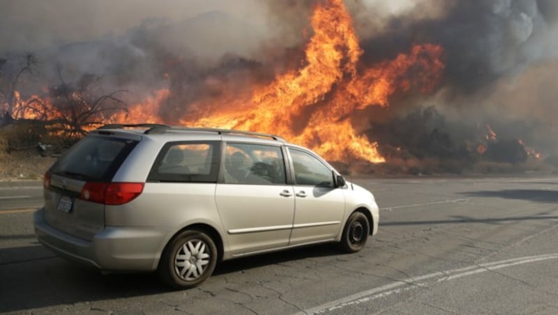 Autofahrer versuchen am Sierra Highway den nahen Flammen zu entkommen. (Bild: AP)