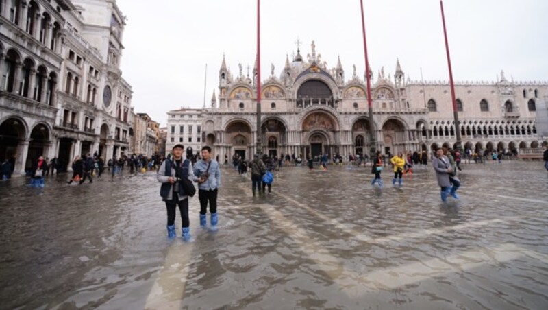 Touristen sind am Samstag in Gummistiefeln am Markusplatz unterwegs. (Bild: AFP)