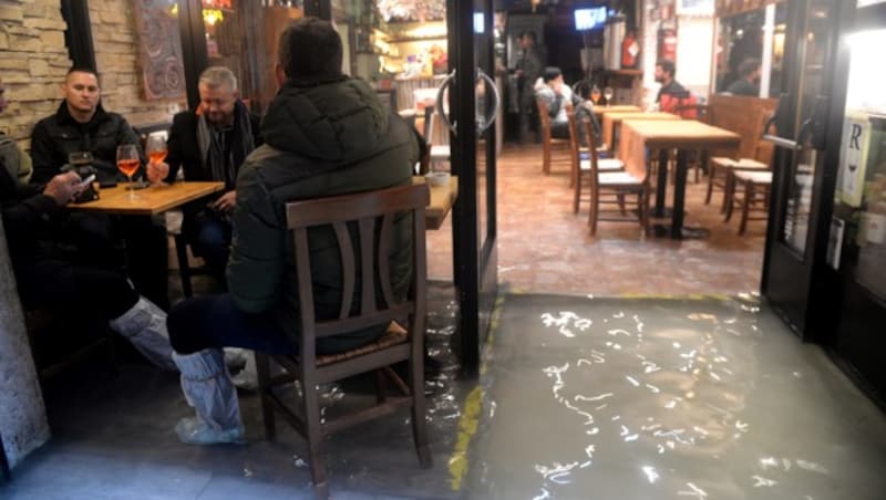 Diese Gäste einer Bar lassen sich vom Hochwasser nicht stören. (Bild: AFP)