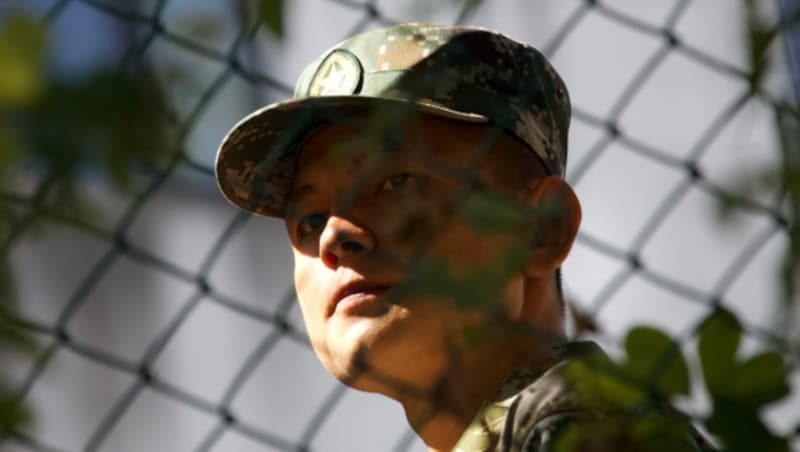 Ein chinesischer Soldat beobachtet von seiner Kaserne aus die Straßenkämpfe in Hongkong. (Bild: AP)