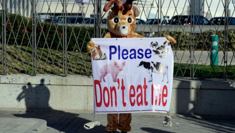 Draußen protestieren vegane Aktivisten, drinnen serviert eine US-Fast-Food-Kette Hamburger. (Bild: AFP)