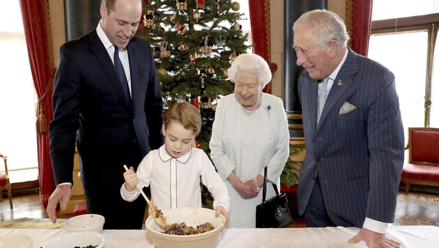 Queen Elizabeth, Prinz Charles und Prinz William sehen Prinz George zu, wie er einen Teig anrührt. (Bild: AP)
