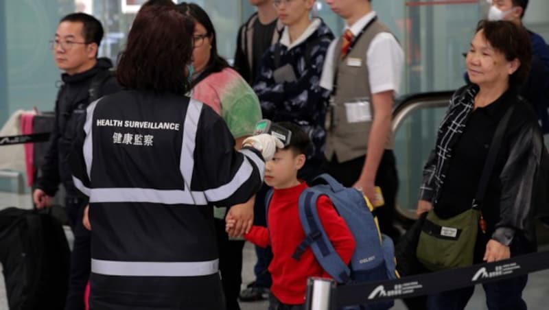 Medizinisches Personal überprüft die Körpertemperatur von in Hongkong ankommenden Flugpassagieren. (Bild: AP)