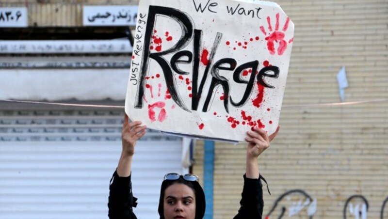 Eine Frau fordert auf einem Plakat Rache. (Bild: AFP)