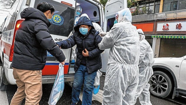 Sanitäter in Schutzanzügen bringen einen möglicherweise mit dem Coronavirus Infizierten in ein Spital in Wuhan. (Bild: AFP)
