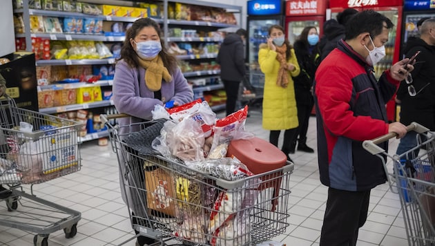 Mit Atemmasken ausgerüstet decken sich diese Konsumenten in Wuhan mit Vorräten ein. (Bild: Arek Rataj)