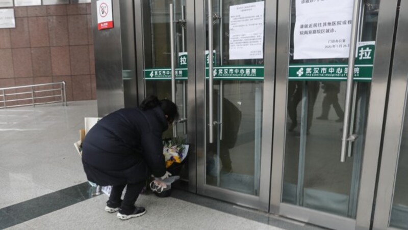 Eine Bewohnerin Wuhans legt Blumen für den verstorbenen Mediziner vor dem Eingang des Krankenhauses ab. (Bild: AFP)