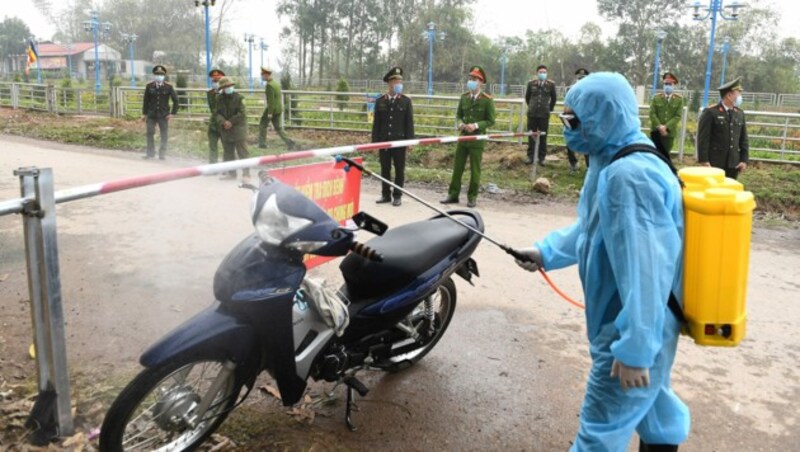 In Vietnam wurden mehrere Dörfer unter Quarantäne gestellt. Behördenvertreter in Schutzanzügen sprühen durchfahrende Fahrzeuge mit Desinfektionsmittel ein. (Bild: AFP)