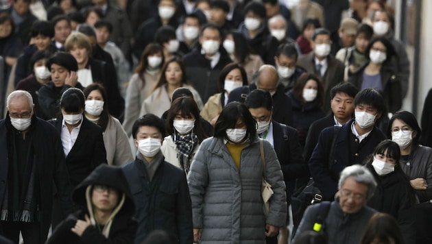Menschen in Tokio - nur die wenigsten tragen keine Atemschutzmasken. (Bild: AP)