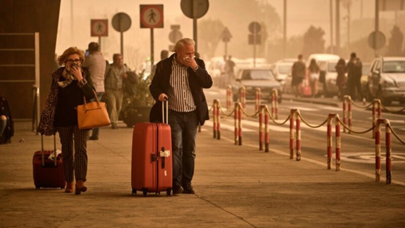 Fluggäste am Flughafen Santa Cruz de Tenerife schützen sich mit Tüchern vor dem feinen Sand. (Bild: Associated Press)