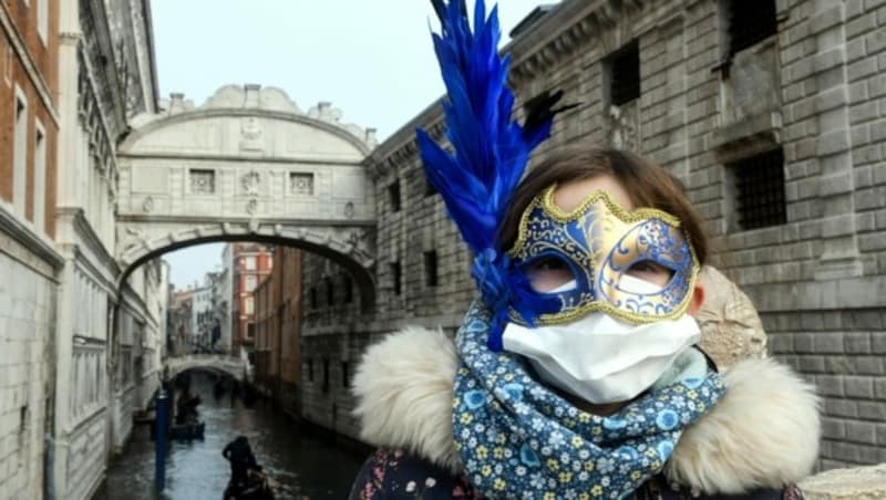 Diese Touristin trägt eine Maske für den Karneval, eine Maske gegen das Virus. (Bild: AFP)