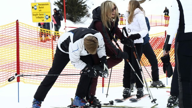 König Willem-Alexander kratzt Schnee aus den Skischuhen seiner Frau, Königin Maxima. (Bild: APA/AP Photo/Matthias Schrader)
