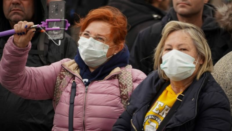 Touristen versuchen sich mit Masken vor dem Coronavirus zu schützen. (Bild: AP)