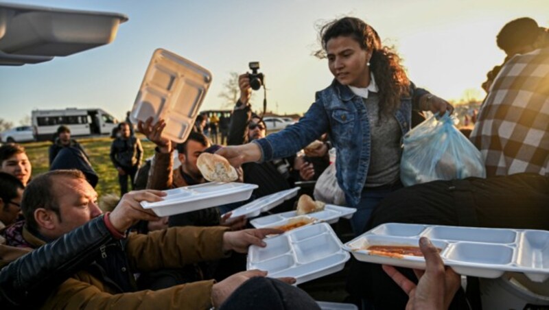 Eine Helferin reicht Flüchtlingen in der Nähe von Edirne Essen. Die Stadt befindet sich im Nordwesten der Türkei. (Bild: AFP)