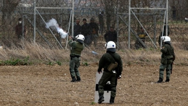 Griechische Polizisten feuern mit Tränengas. (Bild: AP)
