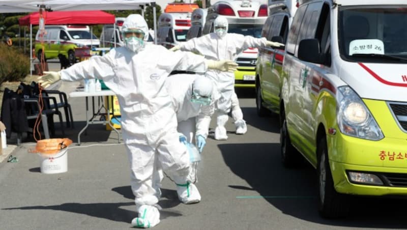 Für den Schutz der Allgemeinheit in Südkorea: Auch Sanitäter werden gründlich desinfiziert. (Bild: AP)