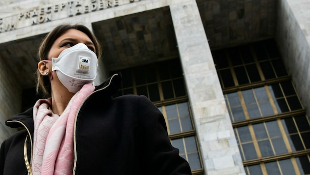 Eine Frau mit Schutzmaske vor dem Justizpalast in Mailand (Bild: AFP)