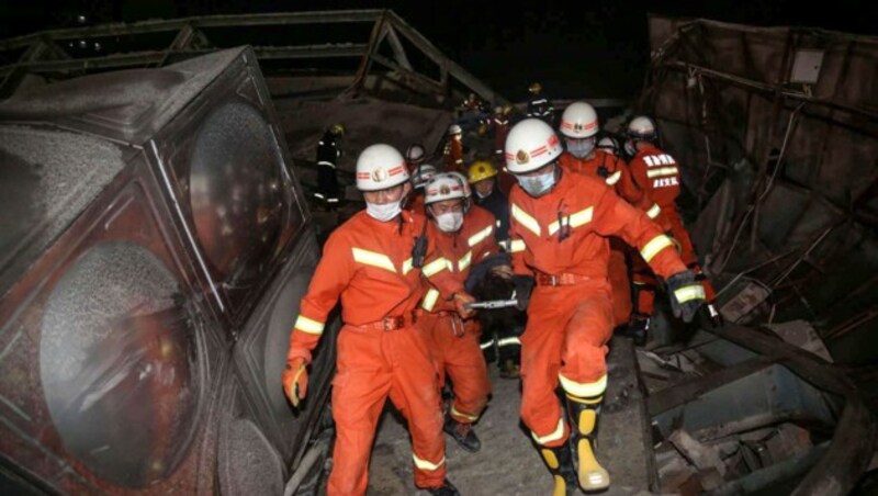 Rescuers carry an injured man (C) out of the rubble of a collapsed hotel in Quanzhou, in China's eastern Fujian province on March 7, 2020. - Around 70 people were trapped after the Xinjia Hotel collapsed on March 7 evening, officials said. (Photo by STR / AFP) / China OUT (Bild: AFP or licensors)