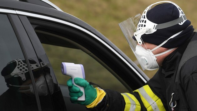 Ein tschechischer Polizist überprüft die Temperatur eines Autofahrers, der von Deutschland nach Tschechien einreisen möchte. (Bild: AFP)