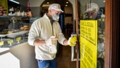 Ein Angestellter desinfiziert die Eingangstür in einem Shop in Codogno in der Lombardei. (Bild: AP)