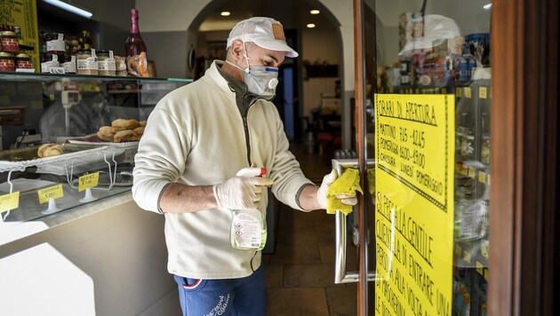 Ein Angestellter desinfiziert die Eingangstür in einem Shop in Codogno in der Lombardei. (Bild: AP)
