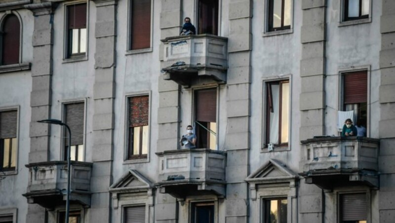 Menschen in Mailand singen und musizieren auf ihren Balkonen. (Bild: AP)