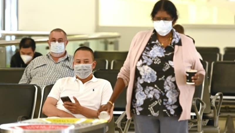 Menschen mit Mundmasken am Flughafen von Sydney (Bild: AFP)