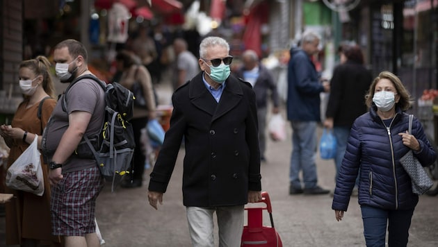 Menschen mit Atemschutzmasken auf einem Markt in Tel Aviv (Bild: AP)