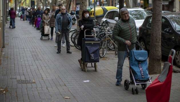 Eine Menschenschlange vor einem Geschäft in Barcelona (Bild: The Associated Press)
