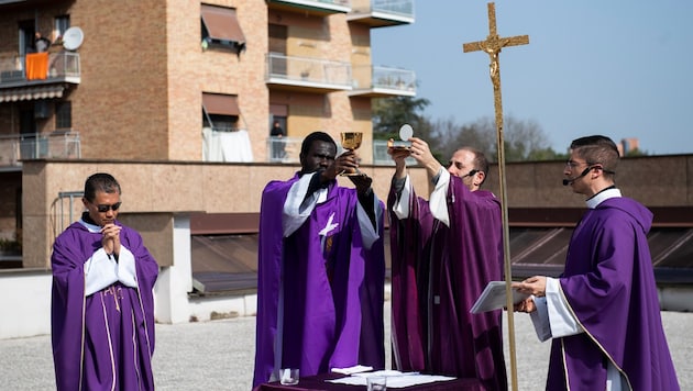 Vier Priester feiern am „Sonntag der Tränen“ die Heilige Messe am Dach einer römischen Kirche. (Bild: APA/AFP/Tiziana FABI)