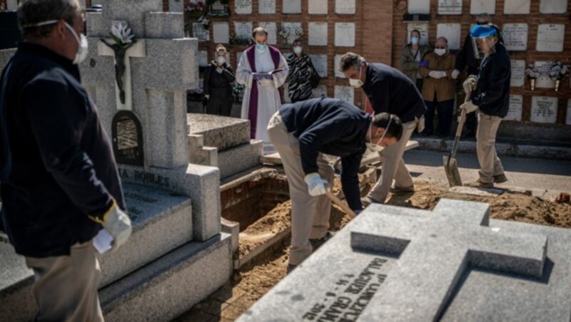 Sicherheitsmaßnahmen bei der Beerdigung eines Covid-19-Opfers (Bild: AP)