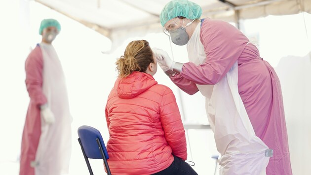 Schutzkleidung entnimmt bei einer Fußgängerin im Coronavirus-Testzentrum eine Probe. (Bild: APA/dpa/Uwe Anspach)