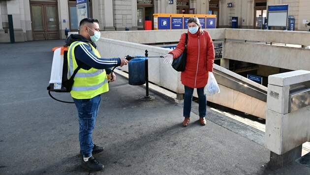 Ein Mitarbeiter desinfiziert die Hände einer Frau auf dem Bahnhof in Budapest. (Bild: AFP)